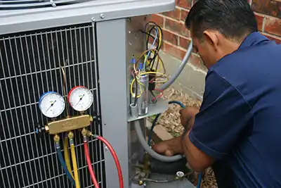 HVAC repair technician conducting AC repair and maintenance and adding refrigerant to an air conditioner.