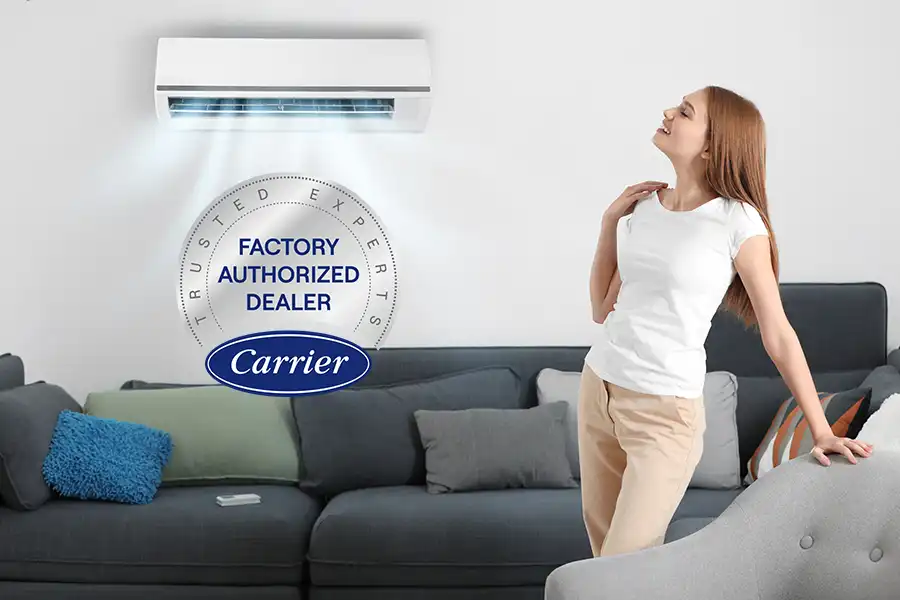 hvac girl copy 2026 FAD Woman enjoying cool air from a wall mounted ductless mini split with a Carrier Factory Authorized Dealer badge